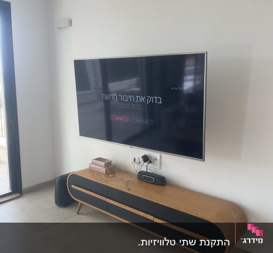 טלוויזיה תלויה על הקיר עם מזנון עץ